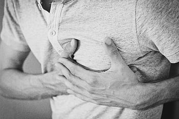 Black and white of a man clutching his chest, indicating discomfort or pain. HD wallpaper