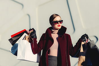 Stylish young woman in sunglasses carrying shopping bags outdoors. Elegant fashion statement. HD wallpaper