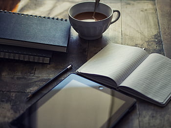 A cozy workspace setup with coffee, notebook, and tablet on a wooden table. HD wallpaper