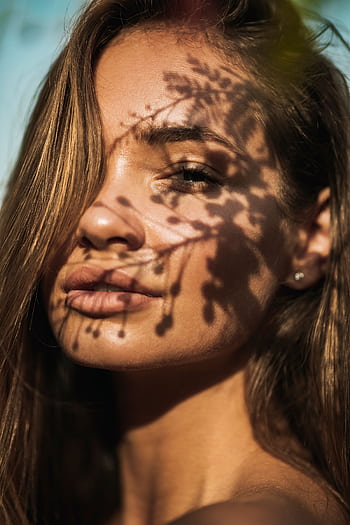 Close-up portrait of a woman with floral shadows on her face, captured in Dubai. HD phone wallpaper