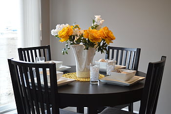 A stylish dining area featuring a round table with vibrant floral centerpiece and modern tableware. HD wallpaper