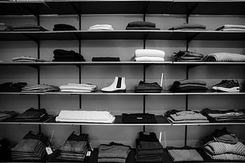 Neatly folded clothing and shoes displayed on shelves in a boutique setting. HD wallpaper