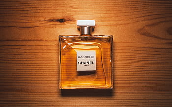 Elegant Chanel perfume bottle displayed on a warm wooden surface, showcasing luxury and style. HD wallpaper