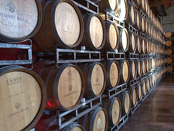 Wooden wine barrels in a Napa, CA winery, ideal for wine production visuals. HD wallpaper