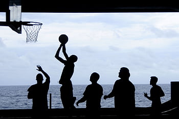 Silhouette of a basketball game played by the ocean, creating a striking visual scene. HD wallpaper