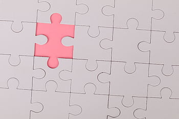 Close-up of an unfinished puzzle with a pink missing piece, highlighting emptiness. HD wallpaper
