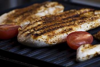 Close-up of grilled chicken breasts with tomatoes sizzling on a barbecue grill, perfect for a delicious meal. HD wallpaper