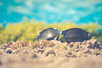 Sandy beach scene with sunglasses and 'summer' spelled in letter tiles, capturing vacation vibes. HD wallpaper