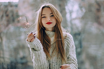 Portrait of a young woman with long hair and red lips holding a sparkler outdoors in Baku. HD wallpaper