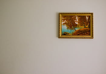 Minimalist interior with a framed landscape painting depicting serene autumn scenery. HD wallpaper