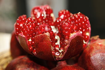 Detailed macro shot of a fresh, vibrant pomegranate exposing its juicy seeds. HD wallpaper