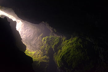 Sunlight streams into a dark cave with moss-covered walls in Smoljan, Bulgaria. HD wallpaper