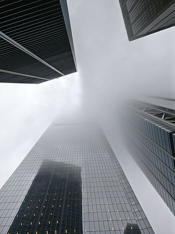 Dramatic view of skyscrapers disappearing into fog in New York City, showcasing urban architecture. HD phone wallpaper