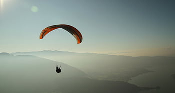 Experience the thrill of paragliding over the stunning Lake Annecy with breathtaking mountain views. HD wallpaper