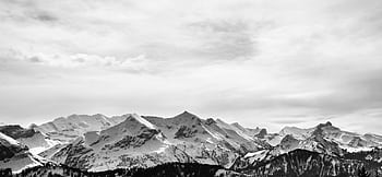 Stunning monochrome landscape of snow-covered alpine mountains under a cloudy sky. HD wallpaper