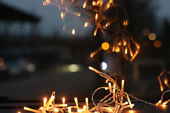 A close-up of warm string lights creating a festive reflection in a dark setting. HD wallpaper