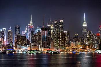 Stunning view of the illuminated New York City skyline reflecting on the Hudson River at night. HD wallpaper