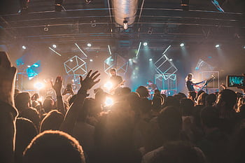 Lively concert scene with crowd, stage lights, and performing musicians at an indoor venue. HD wallpaper