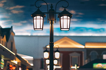 A tranquil street scene with illuminated lamps and architectural backdrop at twilight. HD wallpaper