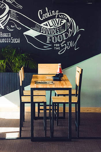 Inviting café interior with wooden chairs and artistic wall design. HD phone wallpaper