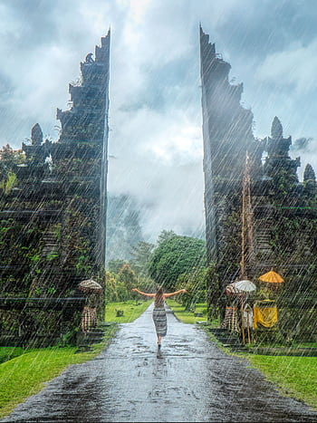 Woman in vibrant rain at iconic Handara Gate, Bali. A magical travel moment. HD phone wallpaper