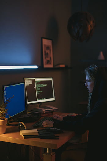 Female programmer working on cybersecurity projects at home, typing code on dual monitors. HD phone wallpaper