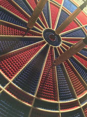 A detailed view of a dartboard with darts in the bullseye, showcasing a competitive sports moment. HD phone wallpaper