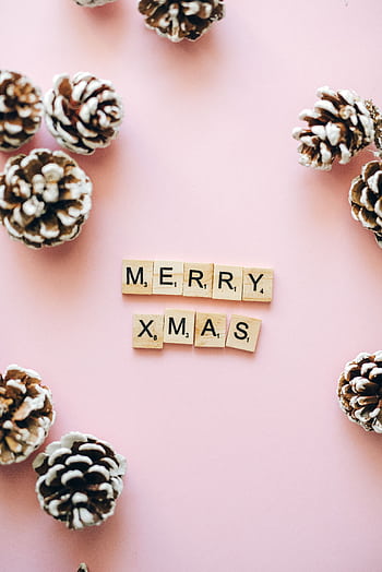 Pink background with pine cones and 'Merry Xmas' in Scrabble tiles for holiday decor. HD phone wallpaper