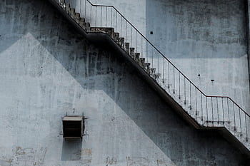 A weathered urban staircase casting dramatic shadows against a concrete wall. HD wallpaper