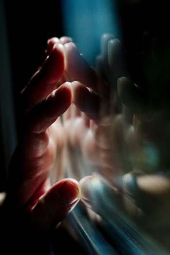 A hand pressing against a glass surface with vivid reflections, creating a moody atmosphere. HD phone wallpaper