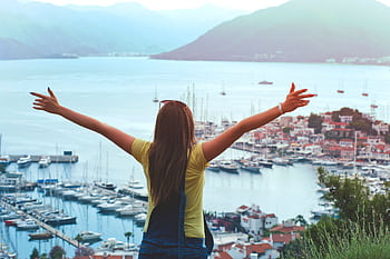 A woman with open arms enjoys a scenic summer view of Marmaris harbor and yachts. HD wallpaper