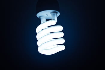Close-up of a glowing spiral energy-saving bulb against a dark backdrop, emphasizing sustainable energy. HD wallpaper