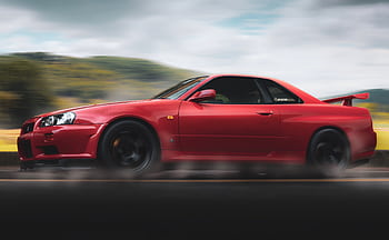 Vibrant red sports car speeds along a scenic highway, showcasing sleek design and performance. HD wallpaper