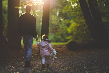 A father and daughter holding hands while walking in a park during autumn. HD wallpaper