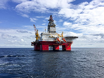 Majestic offshore oil platform under a bright sky in the North Sea, showcasing Norway's energy infrastructure. HD wallpaper
