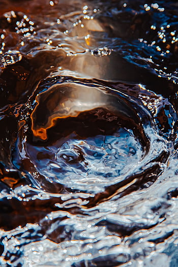 Vivid close-up of water creating a dynamic swirl with varied colors and textures. HD phone wallpaper