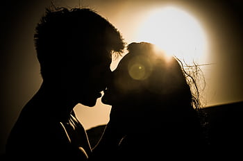 Silhouette of a couple kissing with the sun setting in the background, creating a romantic atmosphere. HD wallpaper