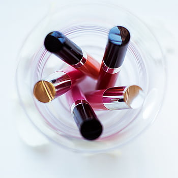 A creative top-down of various lipsticks in a glass, highlighting color and arrangement. HD phone wallpaper