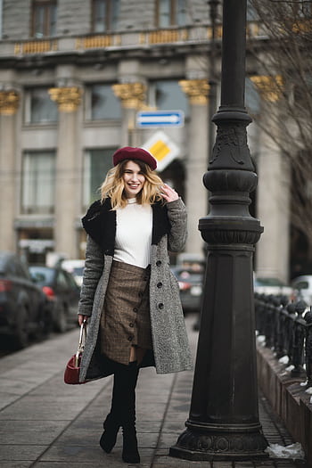Stylish woman in coat and beret walking in city street, showcasing urban winter fashion. HD phone wallpaper
