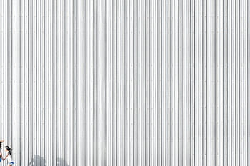 Silhouette of a woman running against a corrugated metallic wall, showcasing minimalist design and light play. HD wallpaper
