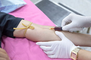A medical professional takes a blood sample from a patient for testing. HD wallpaper
