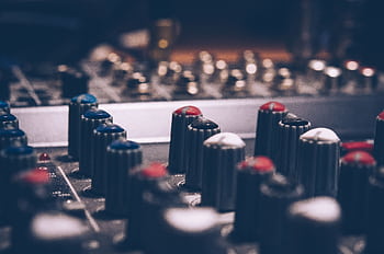Close-up of audio mixer knobs in a dimly lit studio. Perfect for music and technology themes. HD wallpaper