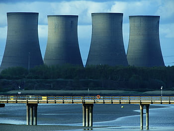 View of industrial cooling towers and a bridge over water, showcasing energy infrastructure. HD wallpaper