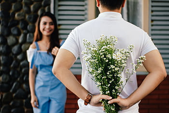 A man surprises his partner with flowers behind his back, symbolizing love and romance. HD wallpaper