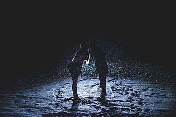 A romantic winter scene depicting a couple kissing under falling snow, creating a beautiful silhouette. HD wallpaper