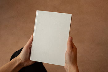 A person holding a blank hardcover book. Perfect for mockup and design templates. HD wallpaper