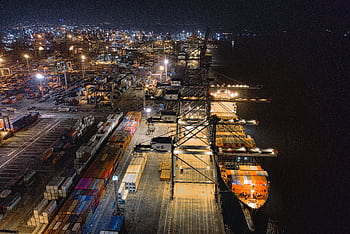 A captivating aerial view of Jakarta's bustling shipping port at night, showcasing vibrant activity. HD wallpaper