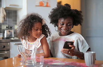 Mother and daughter sharing a joyful moment with a smart in the kitchen. HD wallpaper