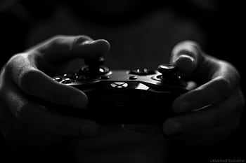 Close-up of hands holding a game controller in a monochrome setting, capturing the essence of gaming. HD wallpaper