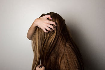 An artistic close-up of a woman's long brunette hair held gently by her hand, emphasizing texture and color. HD wallpaper